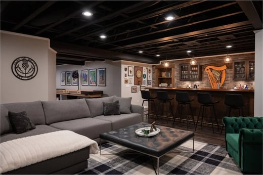 Finished basement living room with seated galley bar, brick back wall and secret door