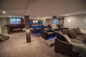 basement finished with carpeting and a theater space with platform seating and a blue led bar