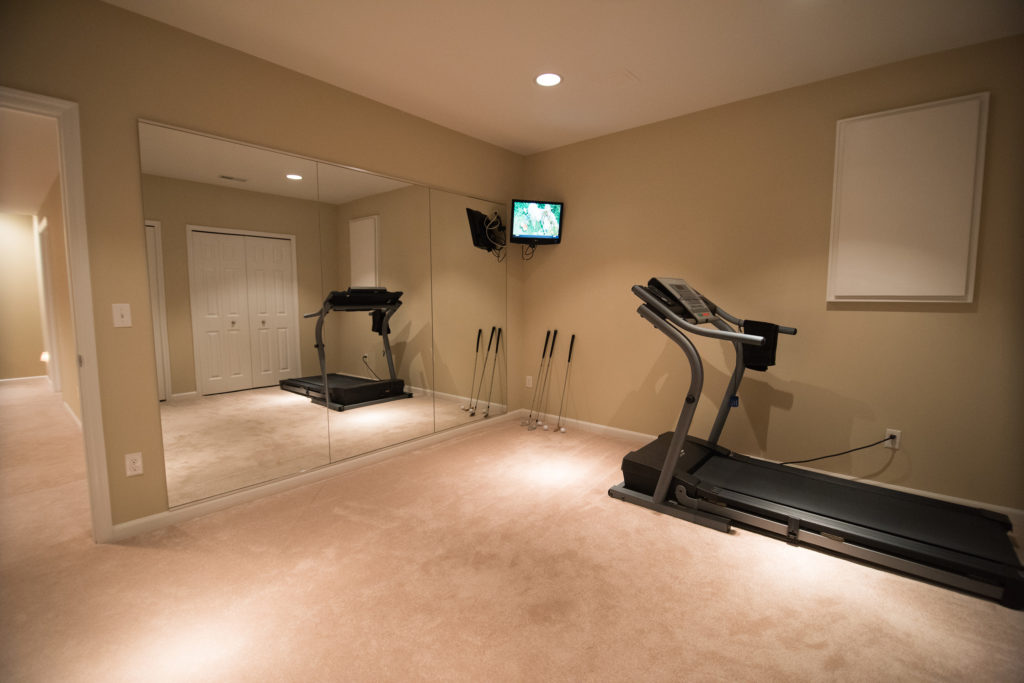 basement fitness room with mirrored wall and carpet