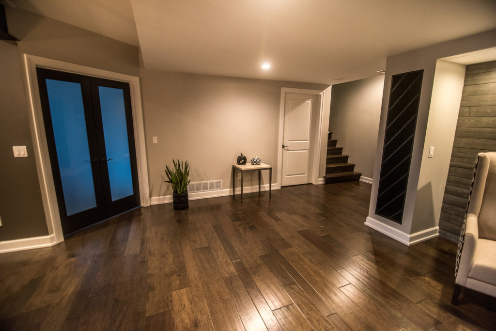 open basement living space leading to spare bedroom with french doors