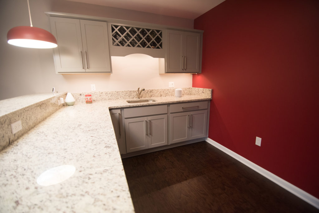 white cabinets and white granite in basement bar with vinyl plank