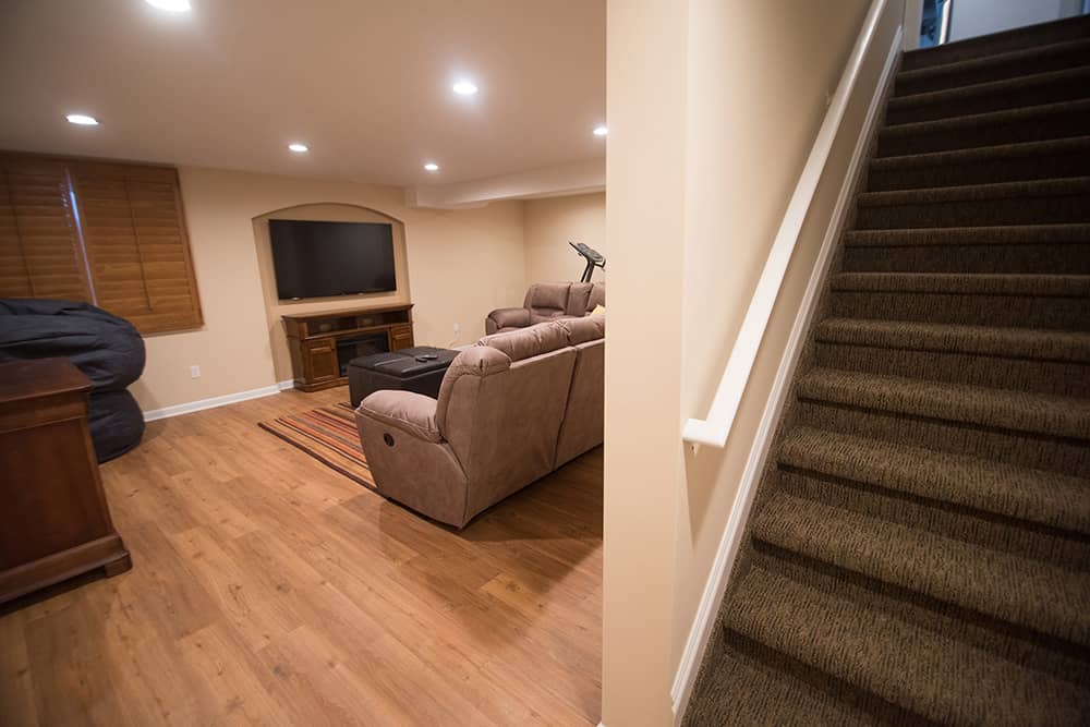 basement staircase leading to finished basement with vinyl plank