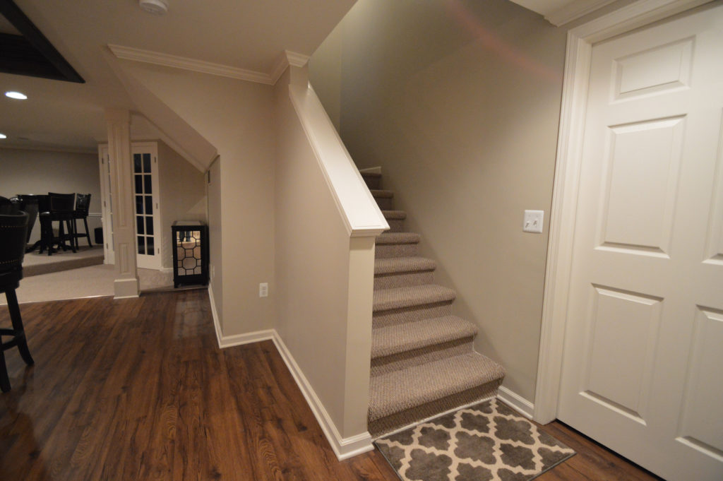 basement staircase with open view railing and carpet on the treads
