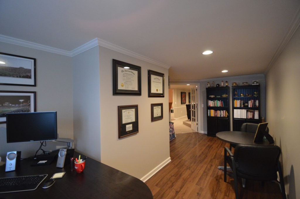 basement home office with vinyl plank flooring and shelving