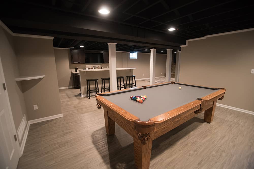 basement with painted ceiling and grey vinyl plank flooring