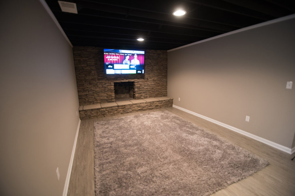 basement living room with brick fireplace and painted ceiling