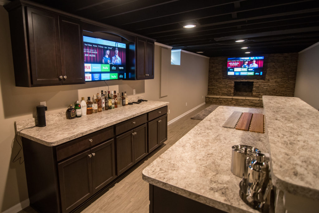 basement bar with dark cabinets and laminate countertops brick fireplace