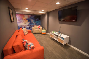 orange couch in finished basement for kids to use as playroom