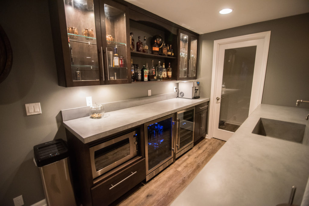 basement bar with back row of cabinets dark colored with rustic vinyl plank flooring