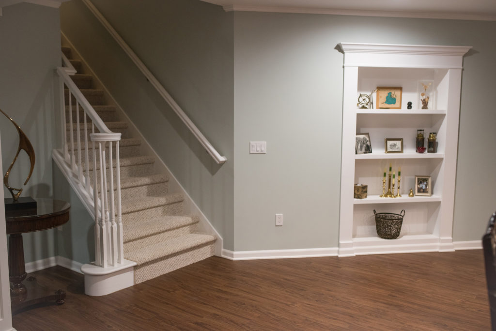 basement staircase with secret bookcase door and vinyl plank flooring