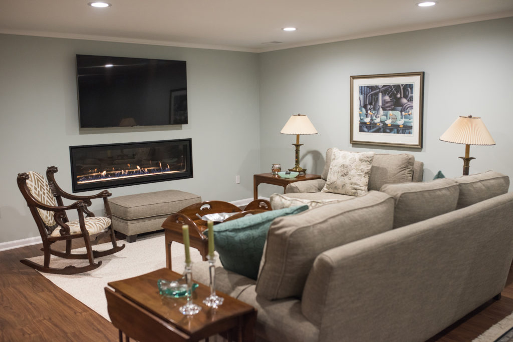 basement living room with sofas and electric fireplace and tv
