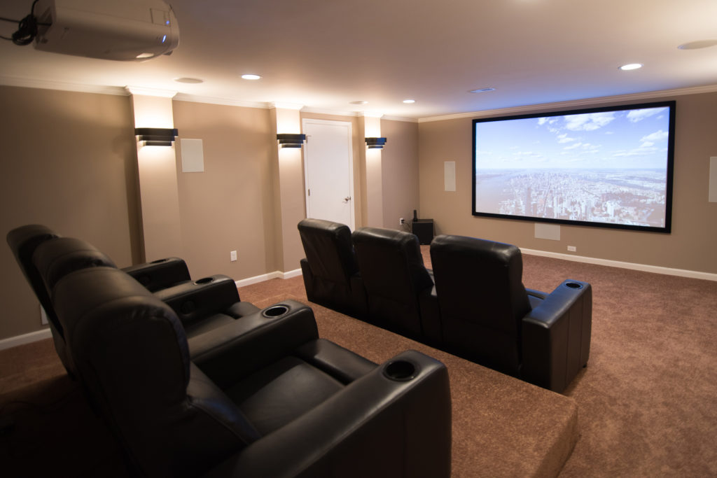basement movie theater with projection screen recliners and platform seating