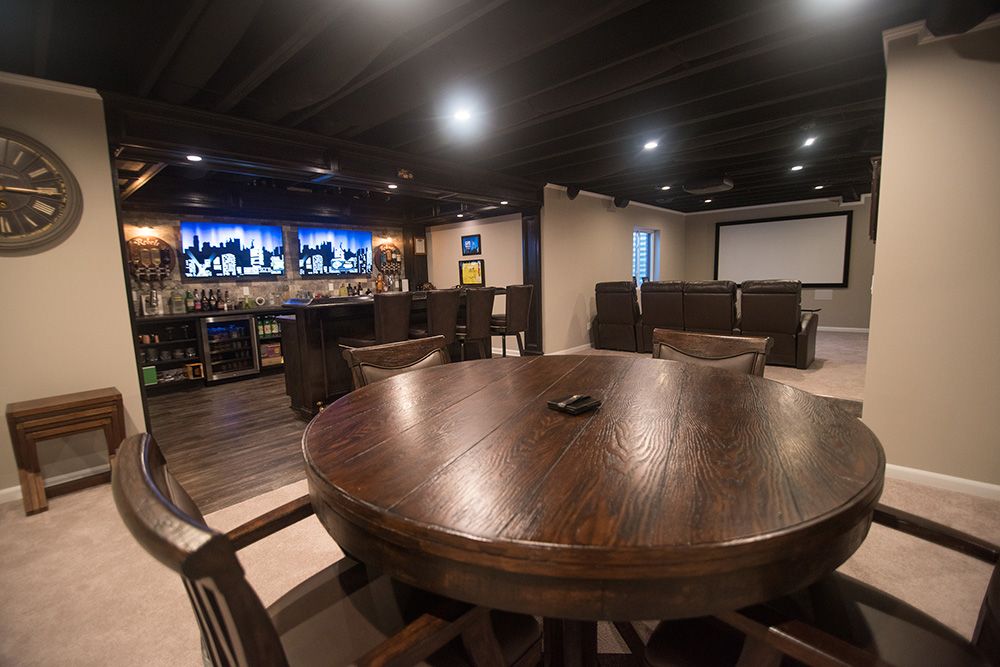 spacious basement with home bar and theater space painted ceiling and carpet
