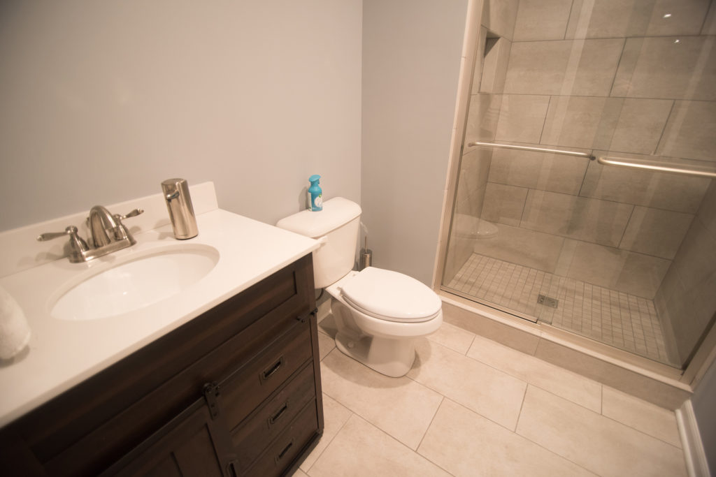 vinyl tile in basement bathroom with dark vanity with quartz countertops
