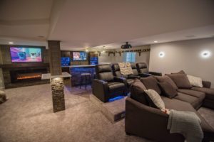 large open finished basement with carpeting and theater with bar behind