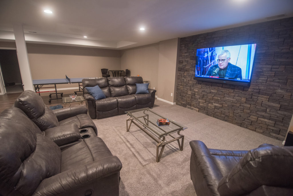 Oakland Township Michigan basement living room accent wall with stone and carpet