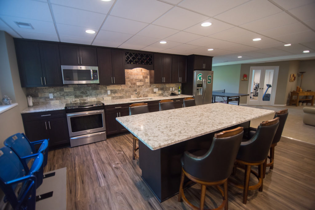 basement kitchen with large granite island and dark maple cabinetry