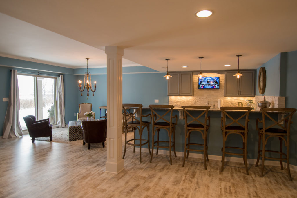 Bright open concept basement bar with light blue walls and beach style design