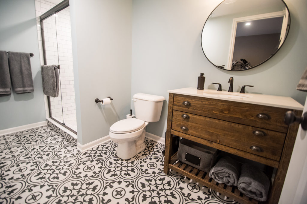 unique bathroom floor tile with black design and stained wood vanity