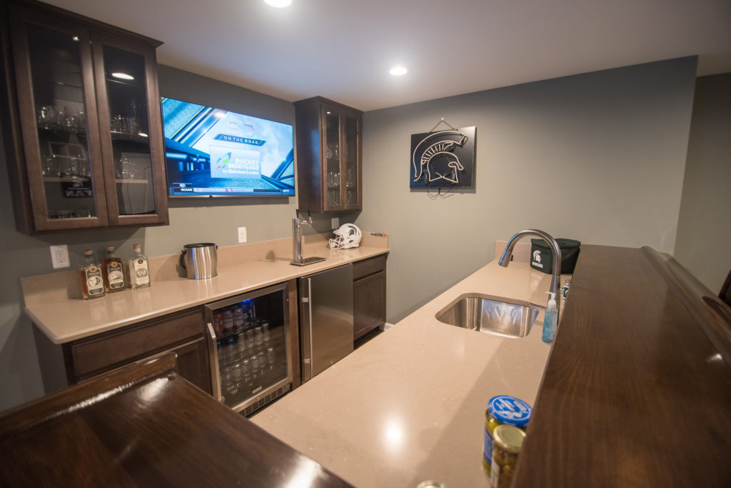 basement bar area with granite countertops and brown cabinets