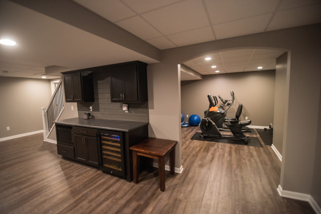 basement bar with adjacent fitness room with archway