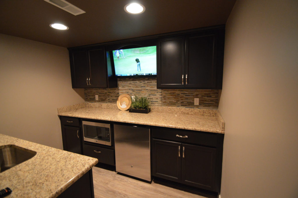 basement bar with dark cabinetry and granite countertops