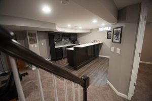 vinyl plank flooring with basement kitchen with dark cabinets and white countertops