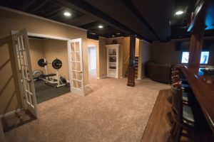 basement with fitness room behind french doors with carpet