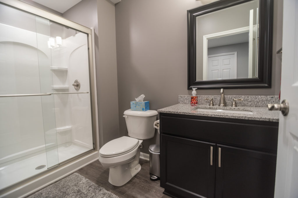 finished bathroom in basement with vinyl plank and shower