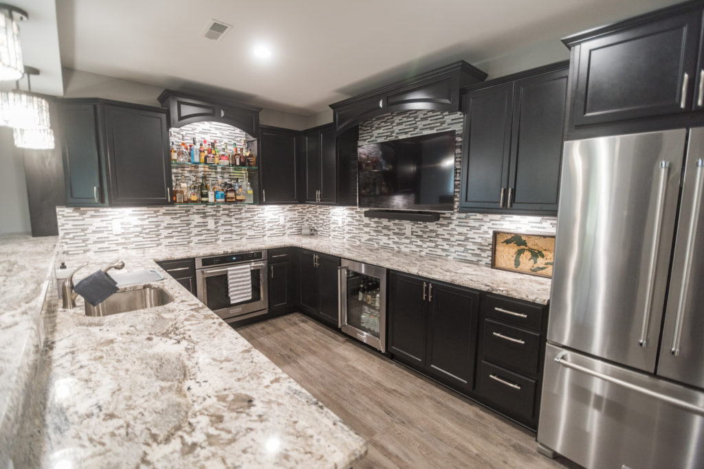 basement kitchen with vinyl plank flooring and dark cabinets