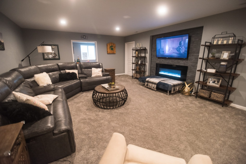 open concept finished basement with stone niche with tv and closed off playroom for kids