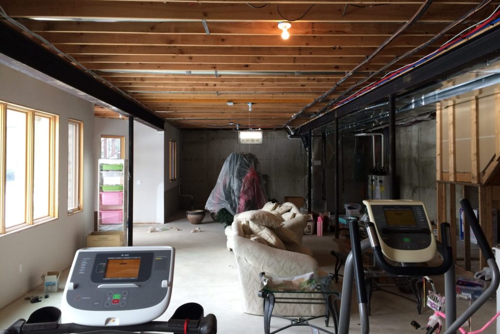 unfinsihed basement with exposed ceiling joists and concrete flooring