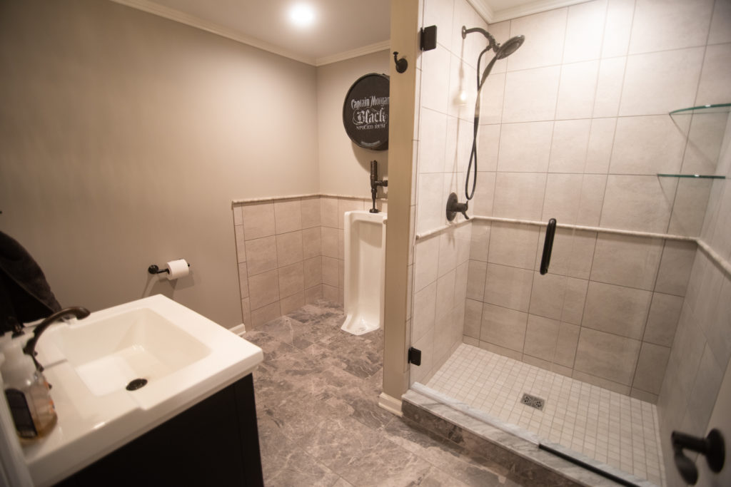 urinal in finished basement with ceramic tile shower