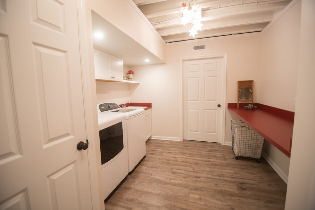 finished basement laundry with painted white ceiling and storage red countertops