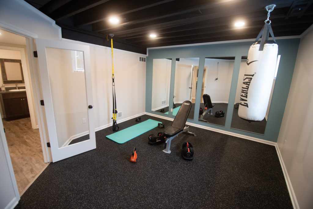 finished home gym in basement with fitness space and mirror panels