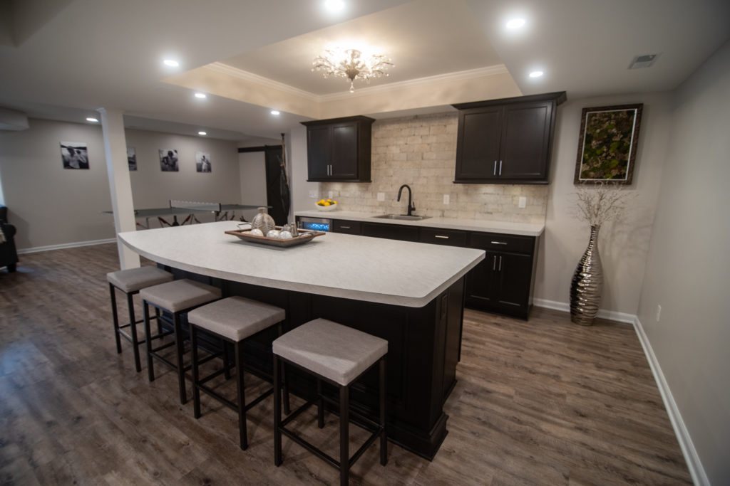 basement bar with white marble laminate countertops and dark brown cabinetry