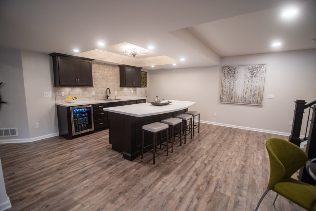 basement bar area with white laminate countertops brown cabinets and light brown vinyl plank flooring