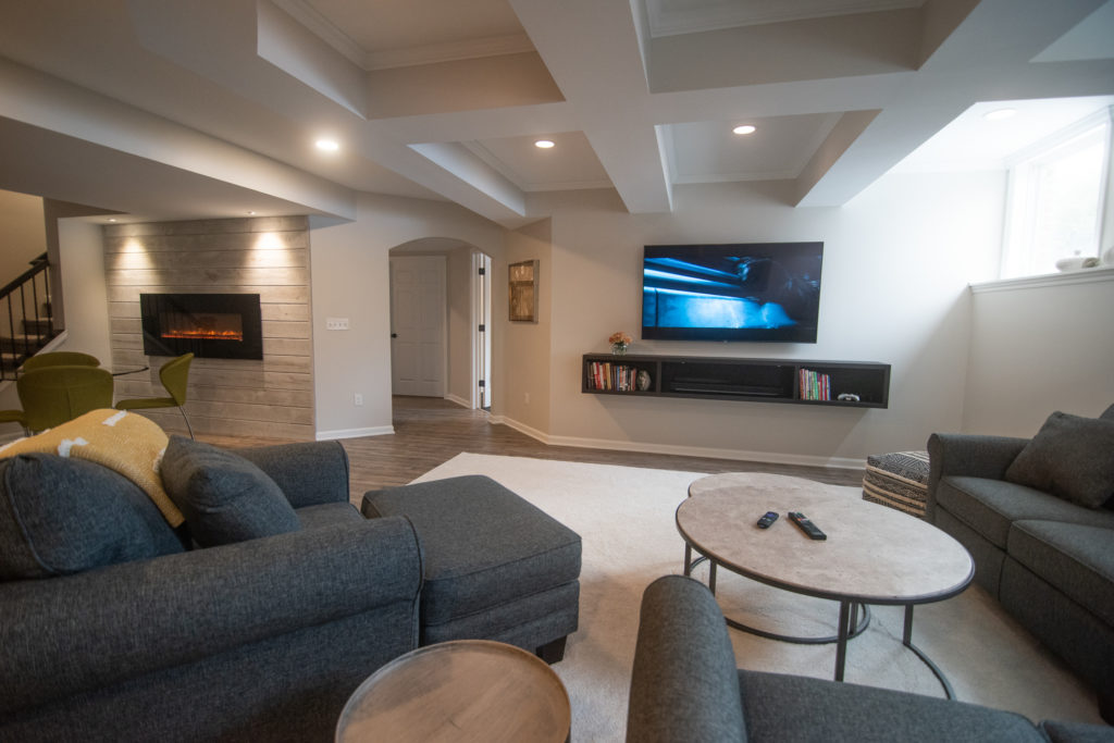 entertainment living room space in basement with ceiling detail and floating console table