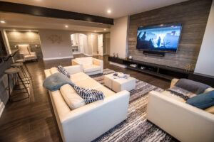 A beautiful finished basement with wood floors and white sofas.