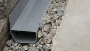 A basement waterproofing channel installed in pea gravel.