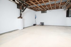 A clean, waterproofed basement with white flooring and walls.