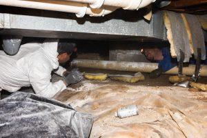 two workers are repairing a home's foundation
