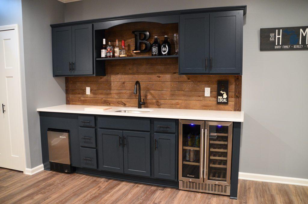 Finished basement wet bar with blue cabinets and wood shiplap backsplash in Berkley, Michigan