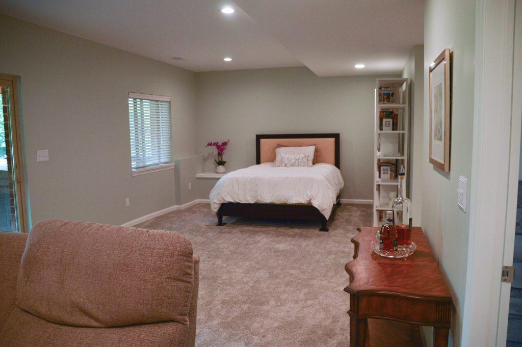 Finished basement view of the guest bed in open area looking from the living room.
