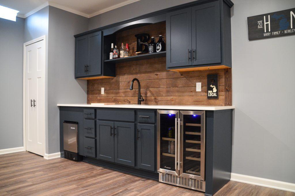 Finished basement wet bar with blue cabinets and wood shiplap backsplash in Berkley, Michigan