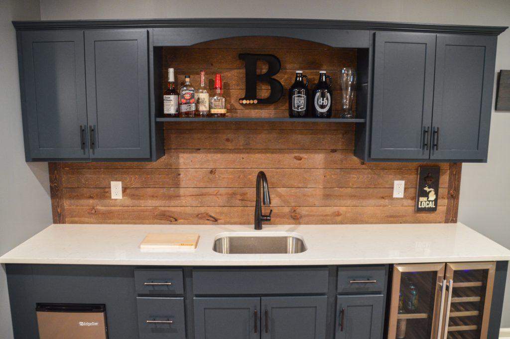 Finished basement wet bar with blue cabinets and wood shiplap backsplash in Berkley, Michigan