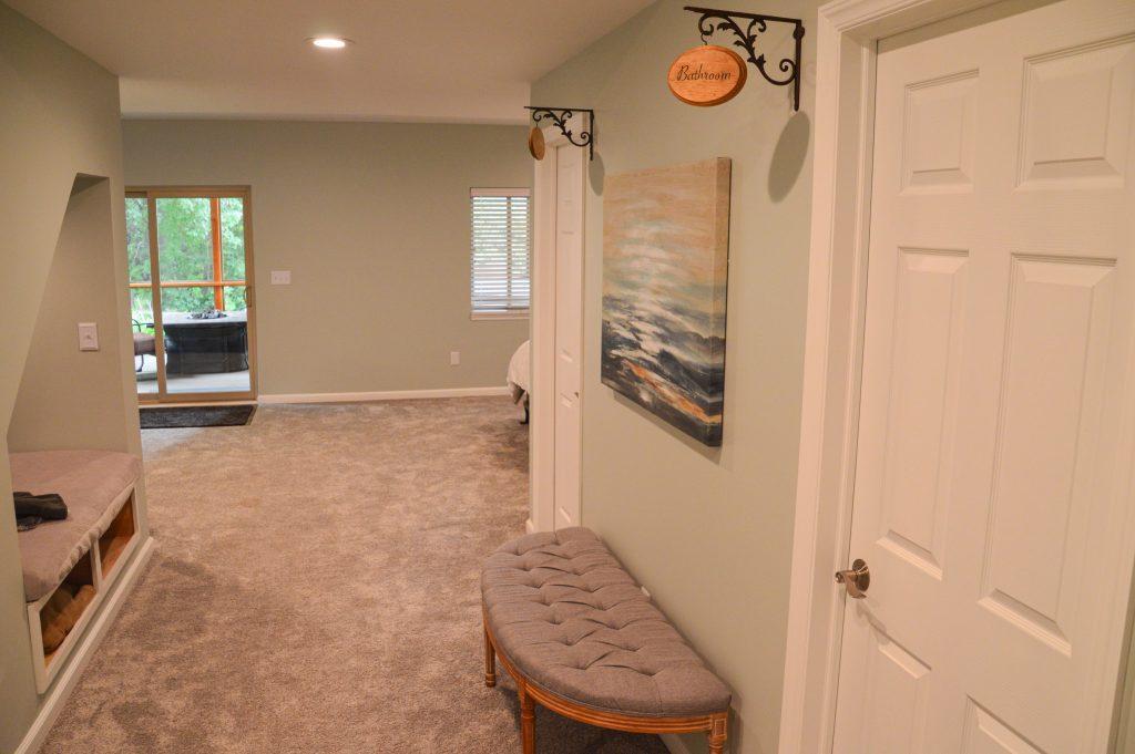 Finished basement hallway looking towards the bathroom and storage doors with custom designed signs displaying what each door leads to.