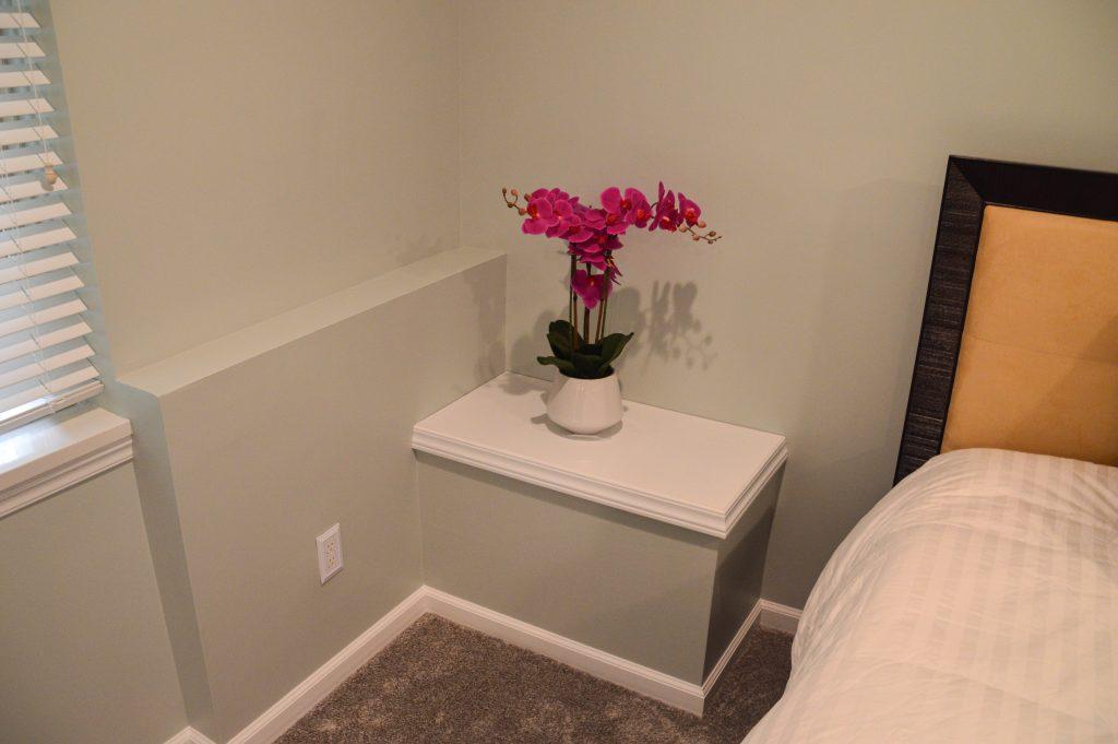 Finished basement guest bed area look of the sump pump box cover.