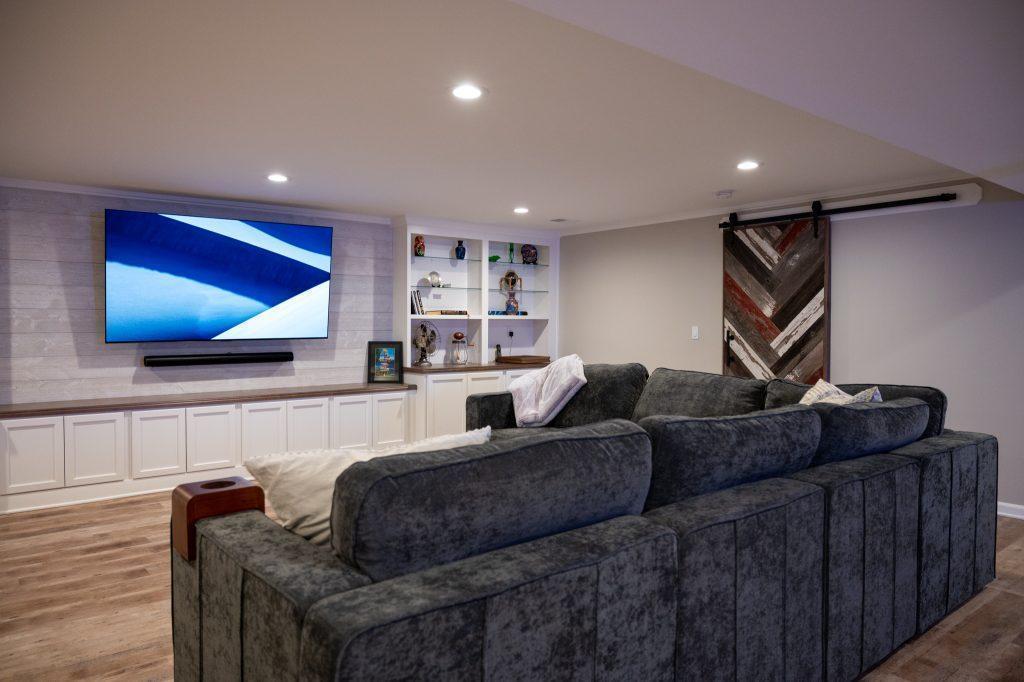 Finished basement living room with white shiplap tv wall and cabinets in Oakland Twp, Michigan