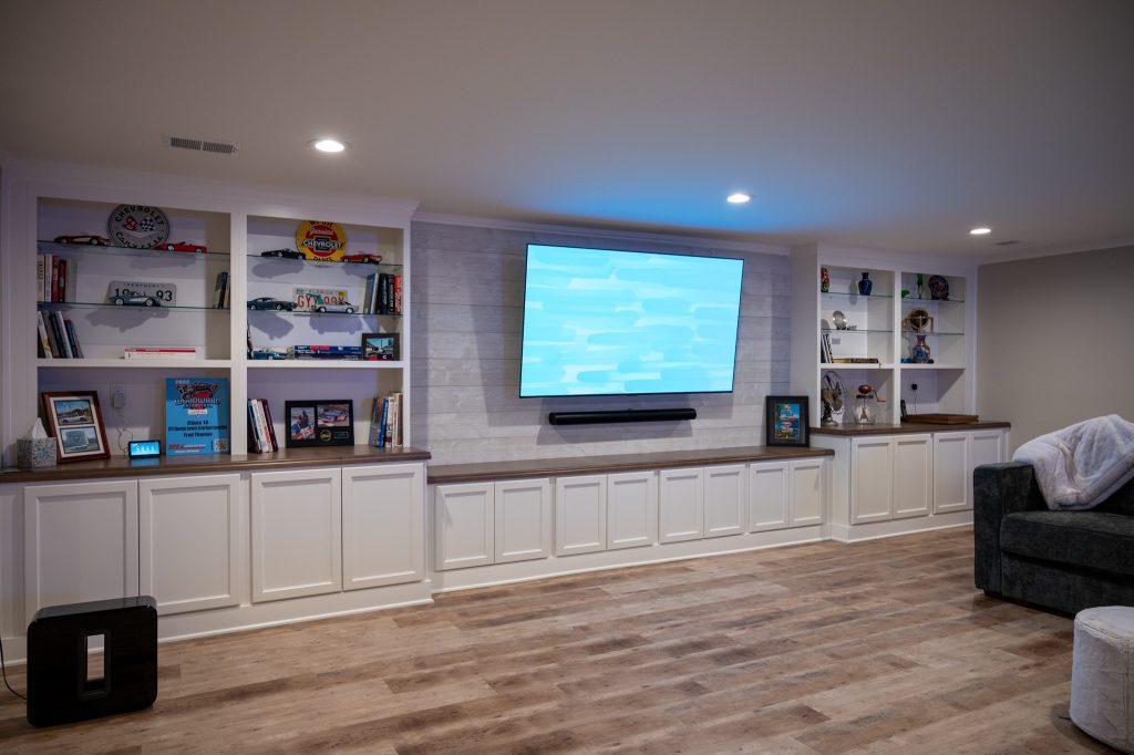 Finished basement living room with white shiplap tv wall and cabinets in Oakland Twp, Michigan